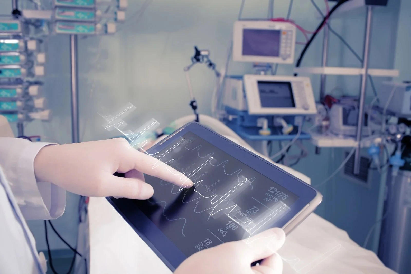 A healthcare professional reviewing respiratory monitoring information beside hospital equipment